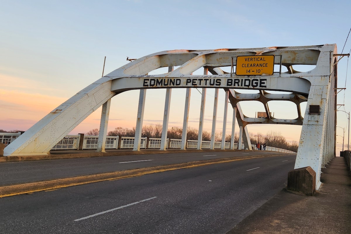 Closeup of the Edmund Pettus Bridge in Selma, Alabama with no cars crossing on the road beneath the bridge's white support arches..